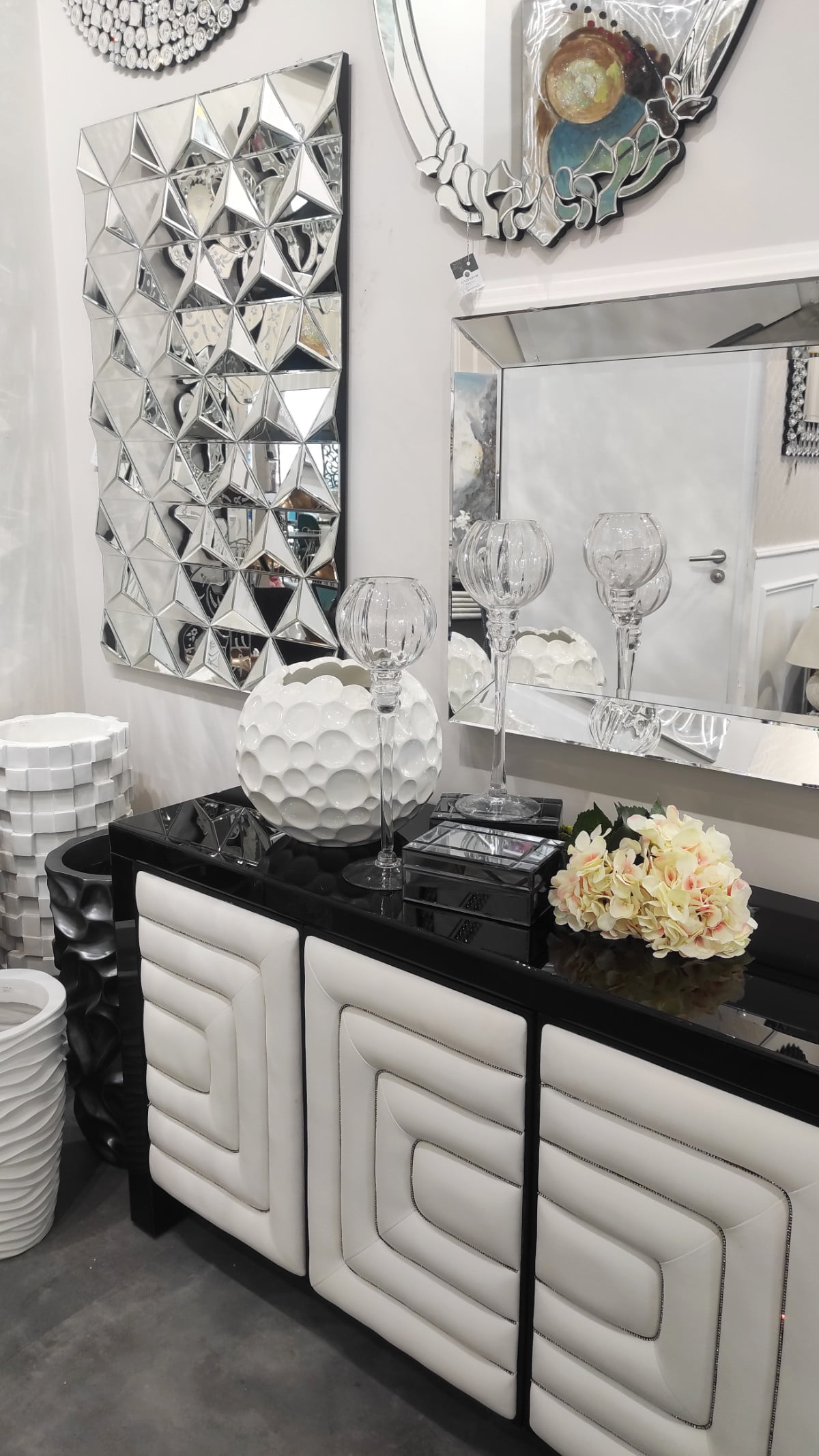 Czarno-biała komoda w stylu glamour w aranżacji z wiszącymi na ścianie dużymi lustrami