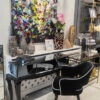Krzesło tapicerowane czarne welur, toaletka szklana na drewnianych czarnych nogach oraz kolorowy obraz abstrakcyjny w wielu kolorach
