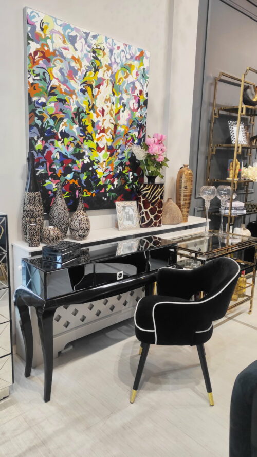 Krzesło tapicerowane czarne welur, toaletka szklana na drewnianych czarnych nogach oraz kolorowy obraz abstrakcyjny w wielu kolorach