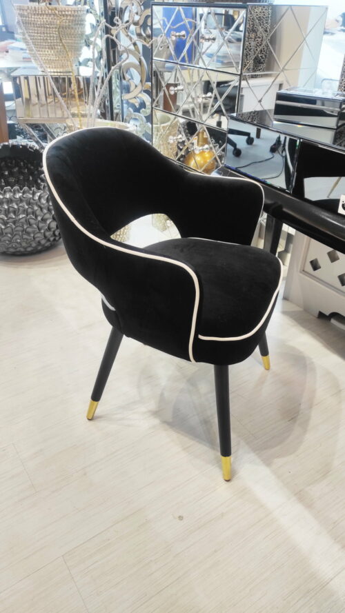 Tapicerowane czarne krzesło obite welurem z białym wykończeniem i złotymi nogami