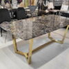 Duży ekskluzywny stół do jadalni wykonany z marmuru i połączonych w jedną złotą ramę nogami