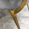 Krzesło Cassari wykończone szarym welurem osadzone na złotych nóżkach